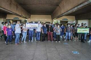 Funcionários com cartazes cobrando o pagamento dos salários (Foto: Marcos Maluf)